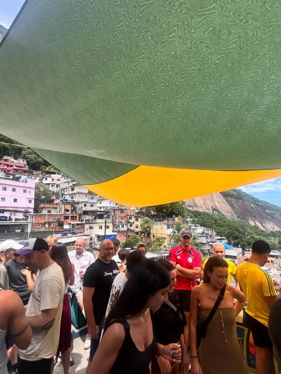 Group of tourists relaxing on a rooftop bar overlooking the favela after the tour