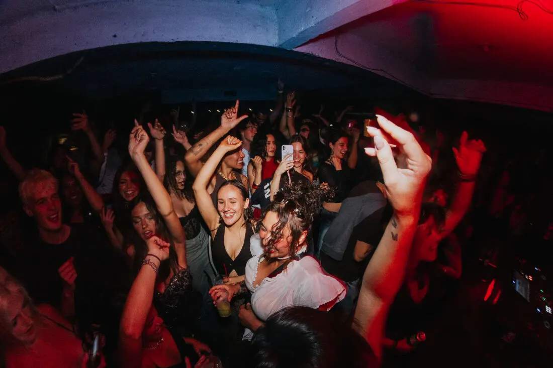 Crowd with hands raised dancing at a baile funk party
