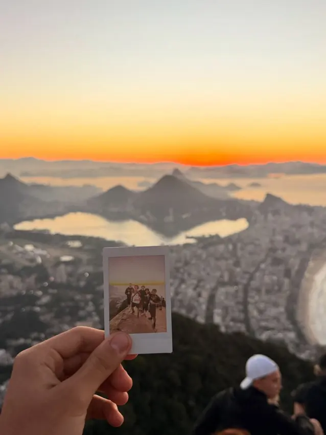 A polaroid photo held up against a sunset view of Rio de Janeiro