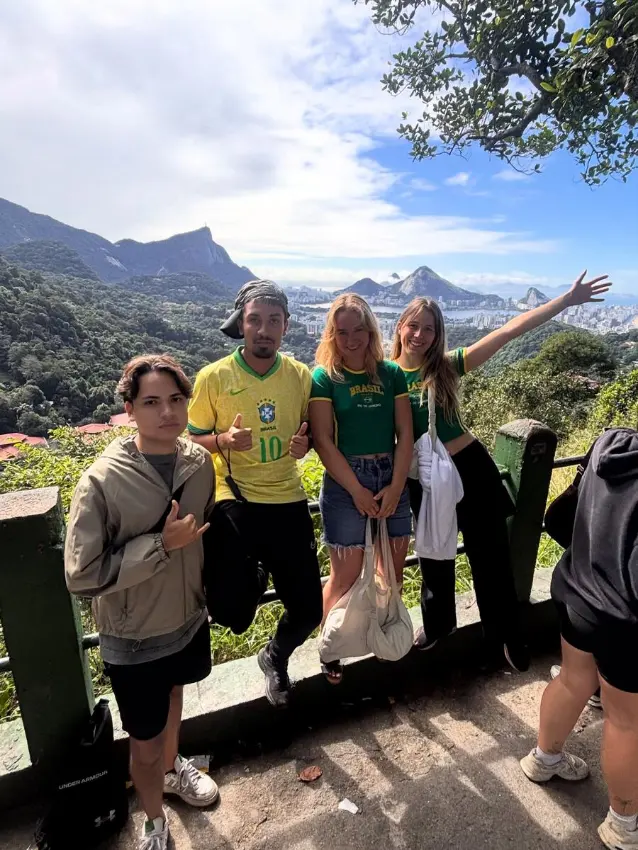 Group of travellers with their guide at a Rio de Janeiro viewpoint, giving a thumbs up