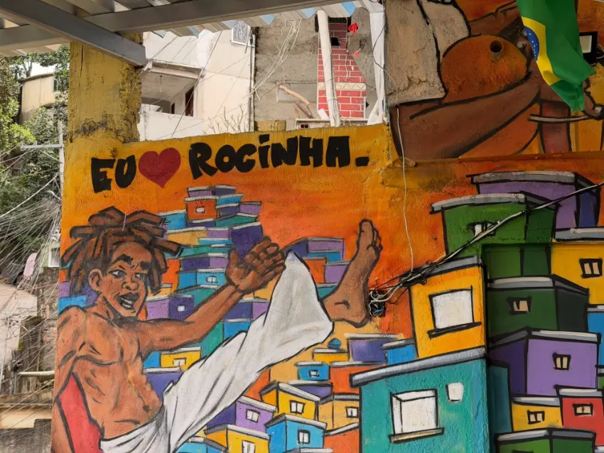 An 'Eu amo Rocinha' mural of a capoeirista painted above the colourful houses of the favela