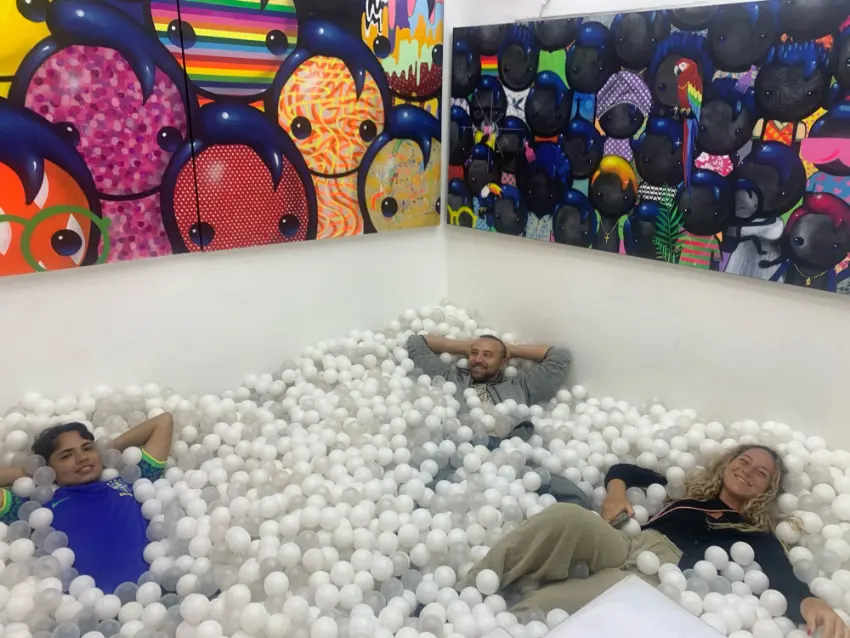 Travellers lying in a ball pit in front of large pop art paintings